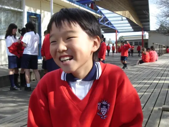 뉴질랜드 학교 교복을 입고 운동장에서 웃는 AECC 학생